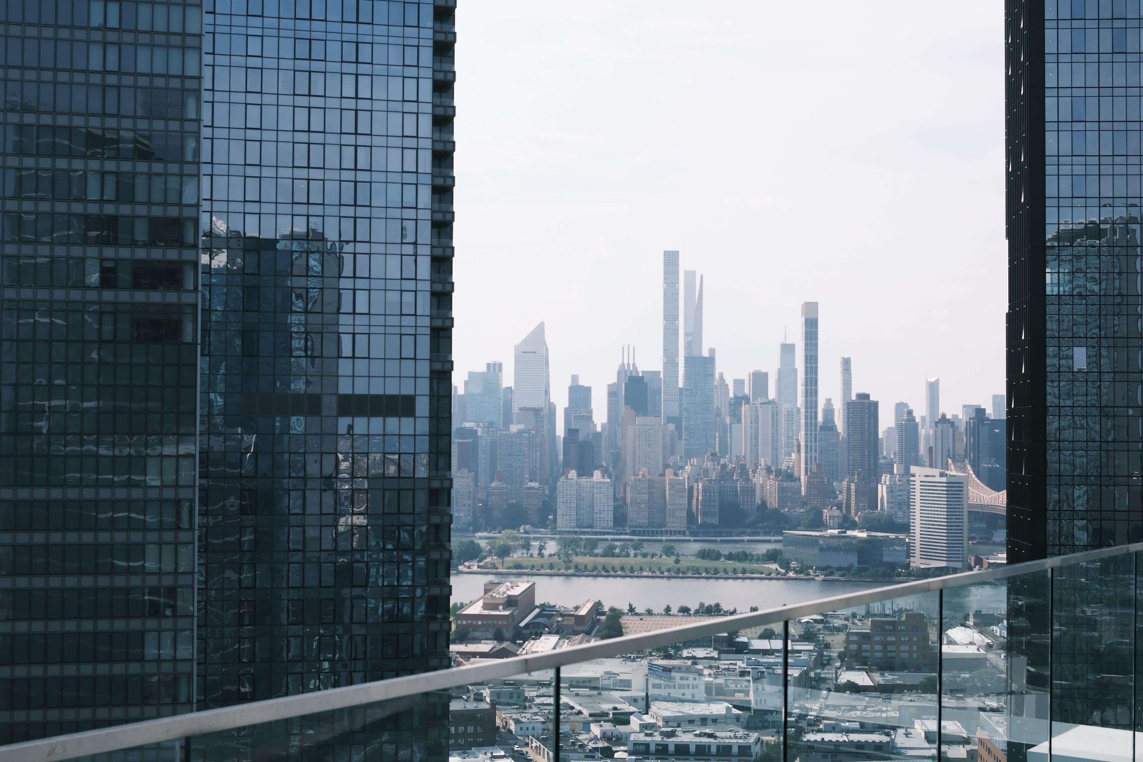 City skyline framed between glass towers from a high-rise balcony